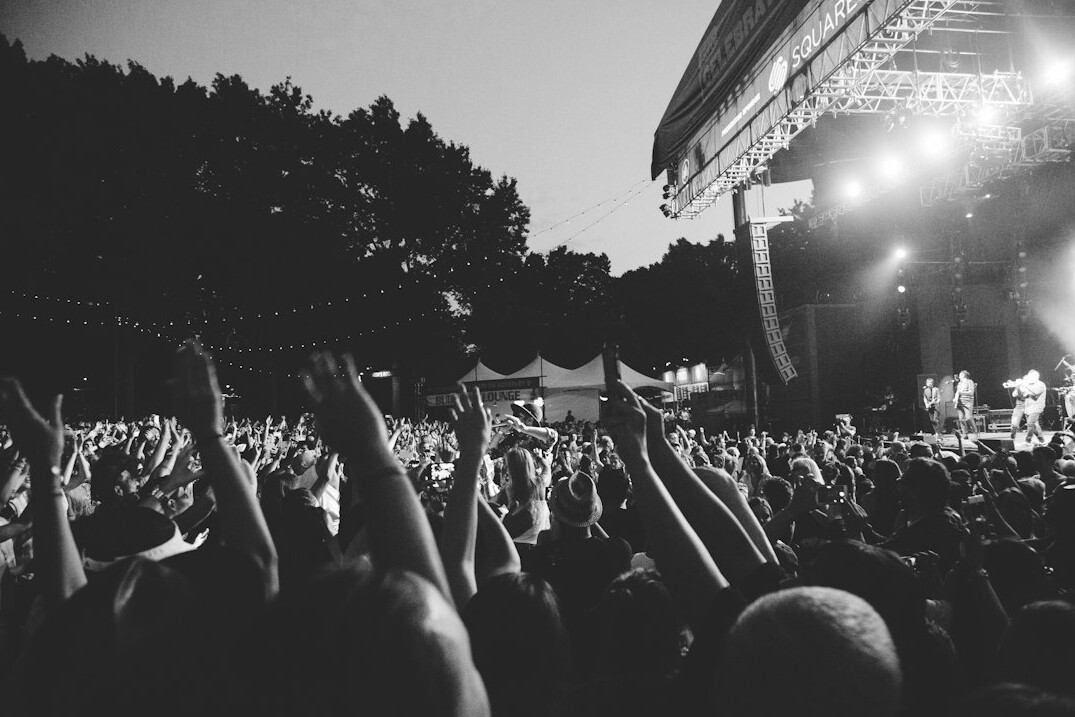 Crowd at an outdoor concert with raised hands